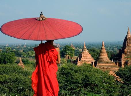 A beautiful scene of a Buddhist monk overlooking temples in Myanmar, Southeast Asia. A Buddhist monk gazes over a view of ancient temples in Myanmar, also known as Burma, in Asia.