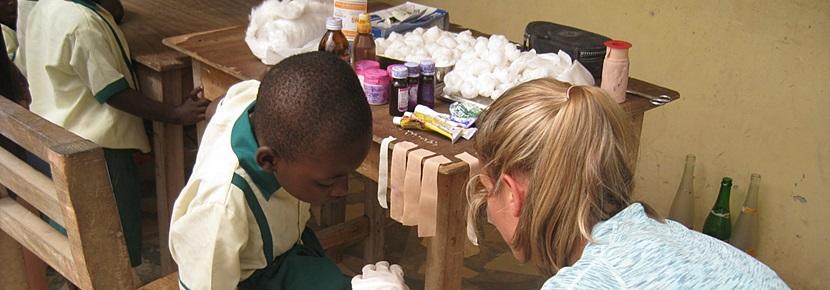 Volunteer in Public Health Abroad with Projects Abroad Volunteer bandaged up a young boy in an outreach project on the Public Health project